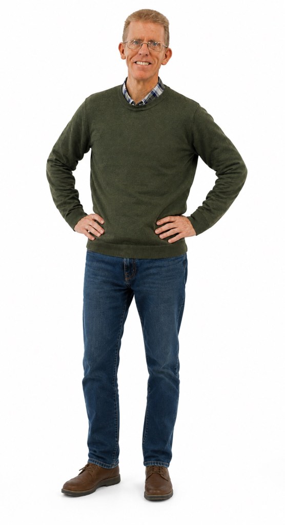 Len Fish standing and smiling in a green sweater and jeans.